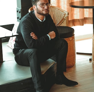 man in black dress shirt sitting on brown chair