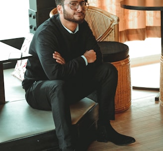 man in black dress shirt sitting on brown chair