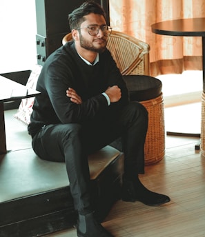 man in black dress shirt sitting on brown chair