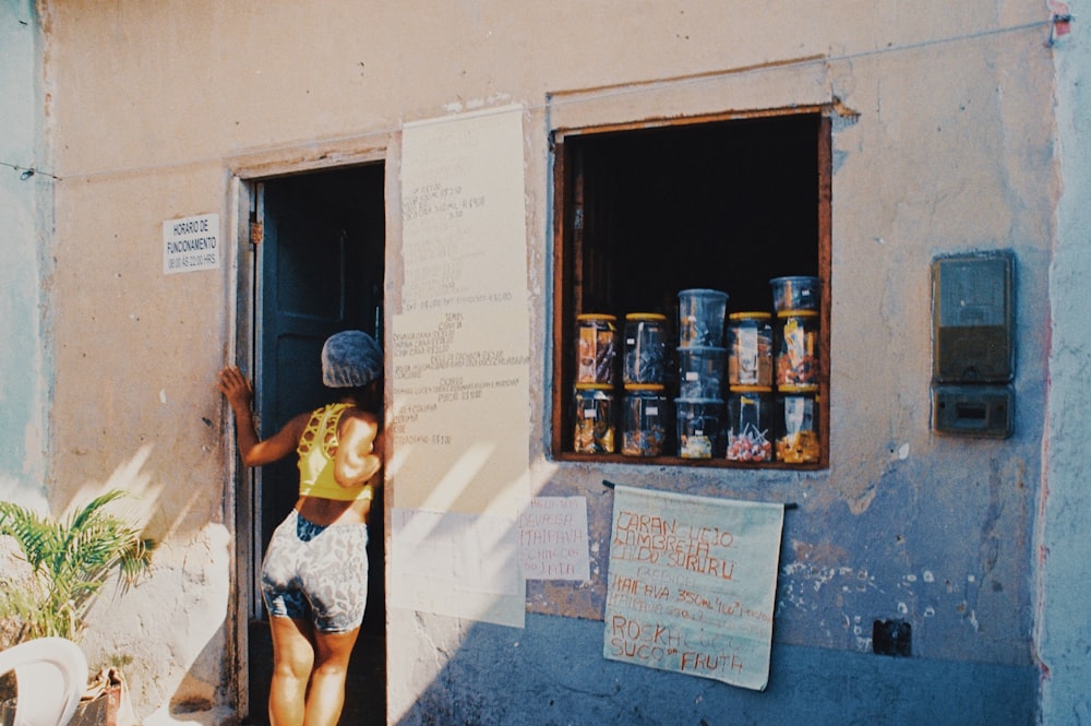 woman in black and white tank top and black panty standing beside brown wooden shelf