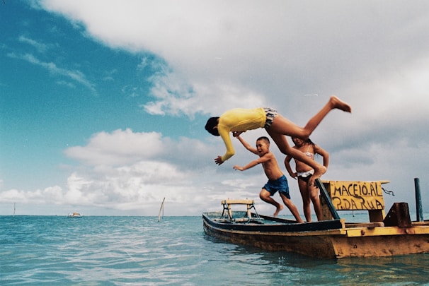 2 women in yellow and blue bikini on brown wooden boat on blue sea during daytime