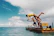 Kids laughing while splashing in a cruise ship pool under a bright blue sky.