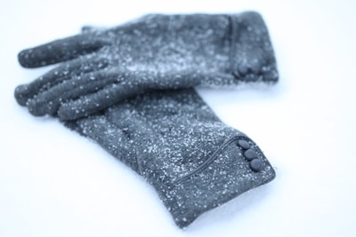 Winter accessories like gloves and scarves arranged on a frosted surface with subtle snowflake patterns