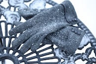 A pair of gloves resting on a wooden table with winter decor.