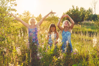 3 girls in blue and white floral dress standing on pasture during daytime