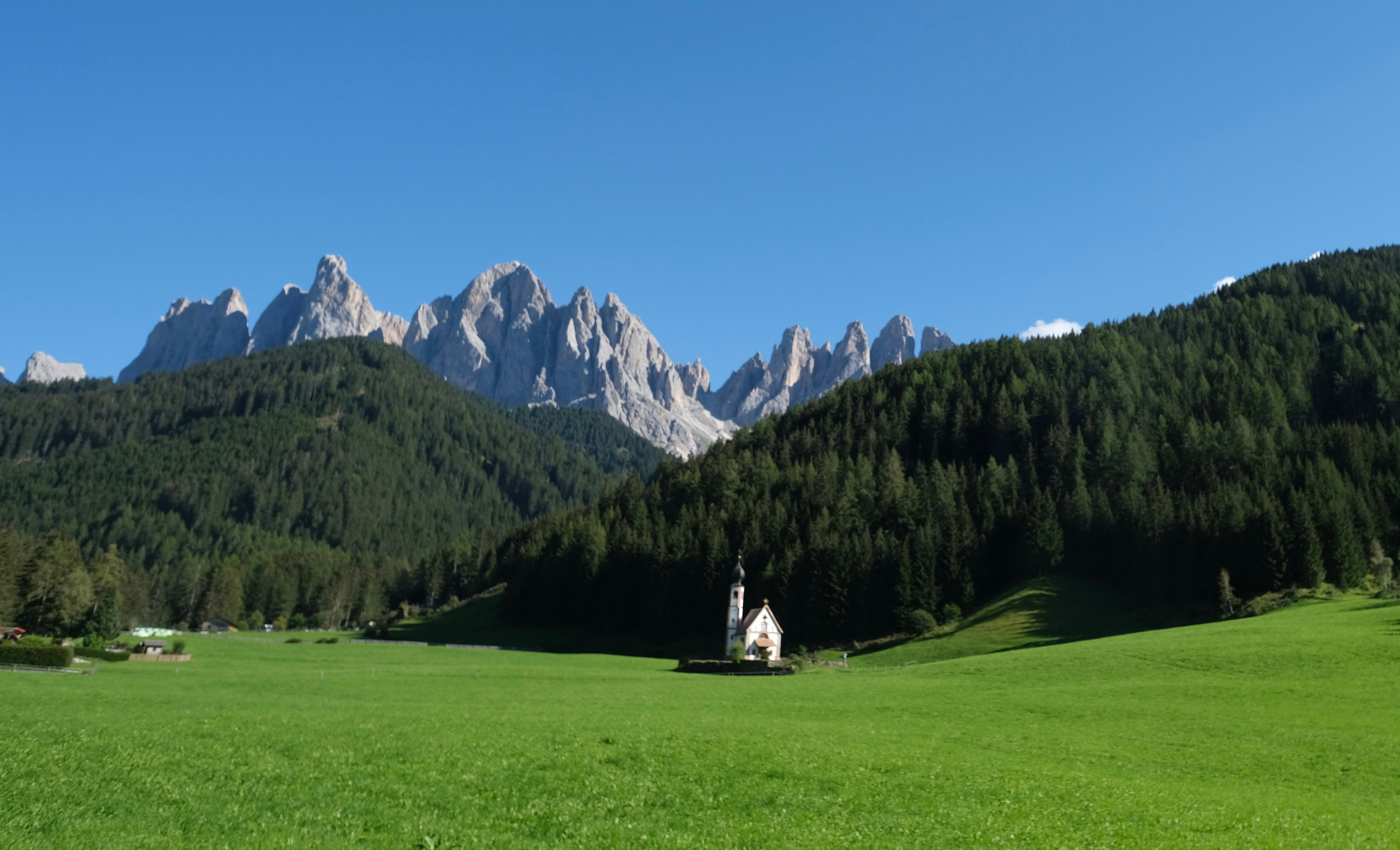 white and brown house on green grass field near green trees and mountains during daytime