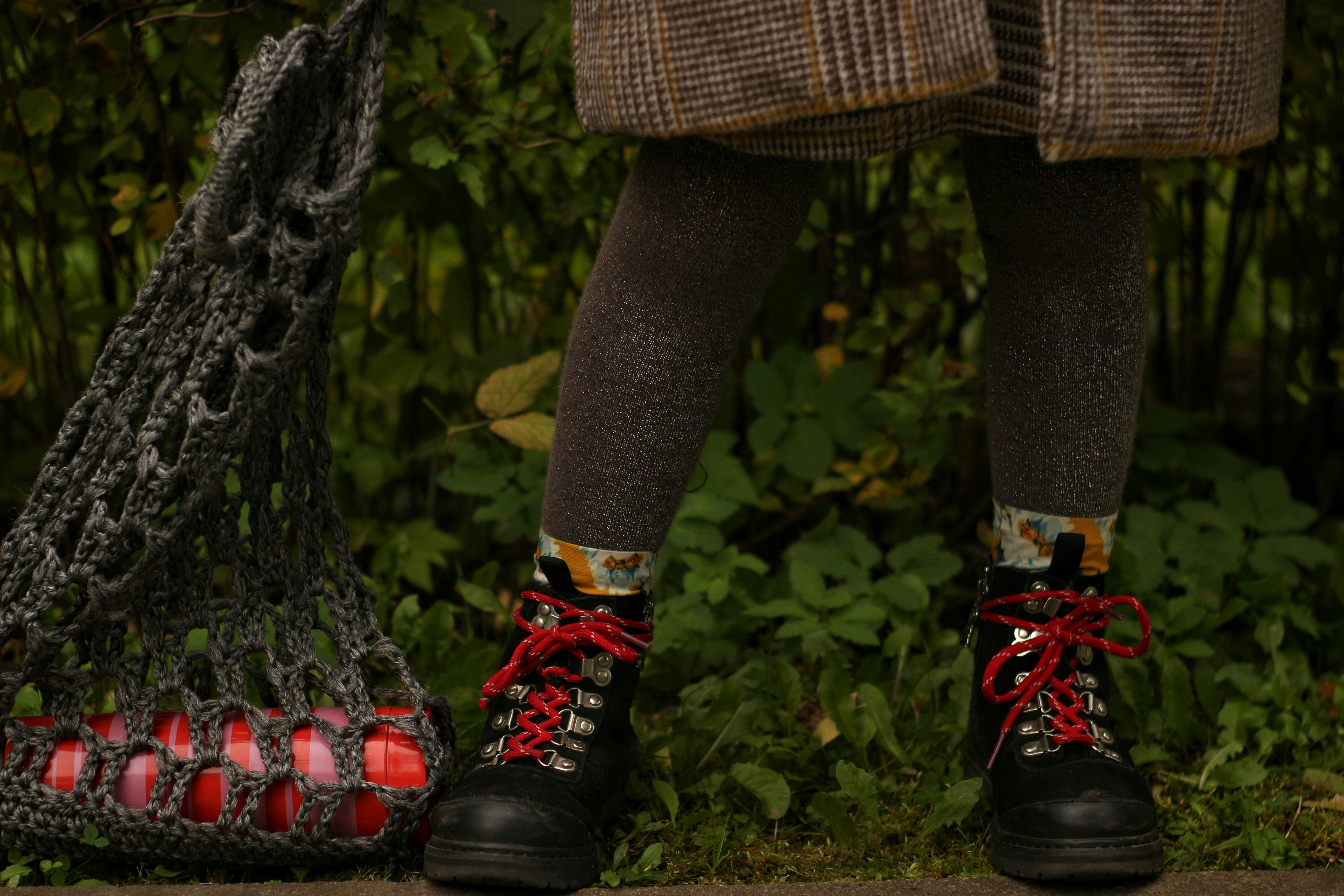 person in black leather boots standing on tree trunk