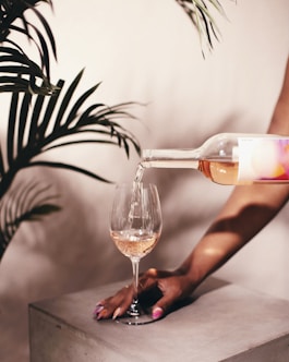person pouring wine on wine glass