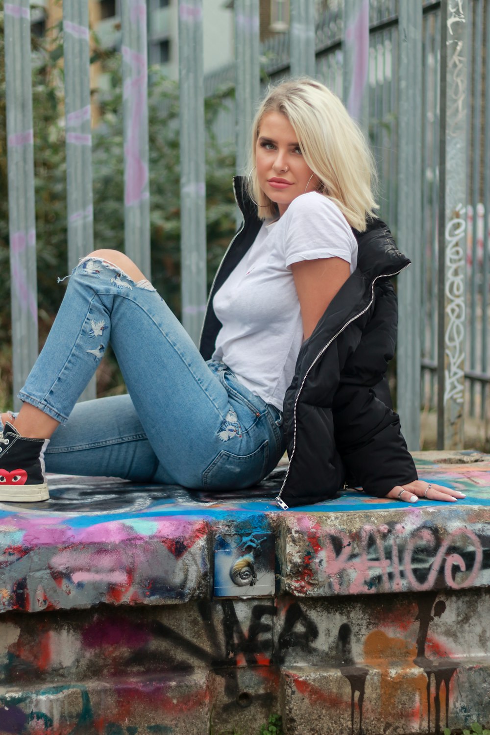 woman in black jacket and blue denim jeans sitting on red and black skateboard