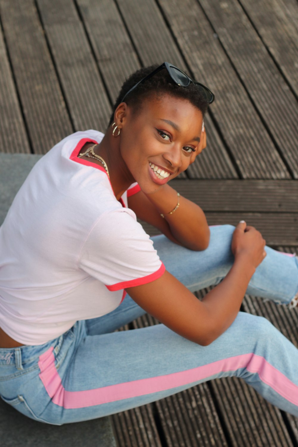 woman in white crew neck t-shirt and blue denim jeans sitting on brown wooden bench