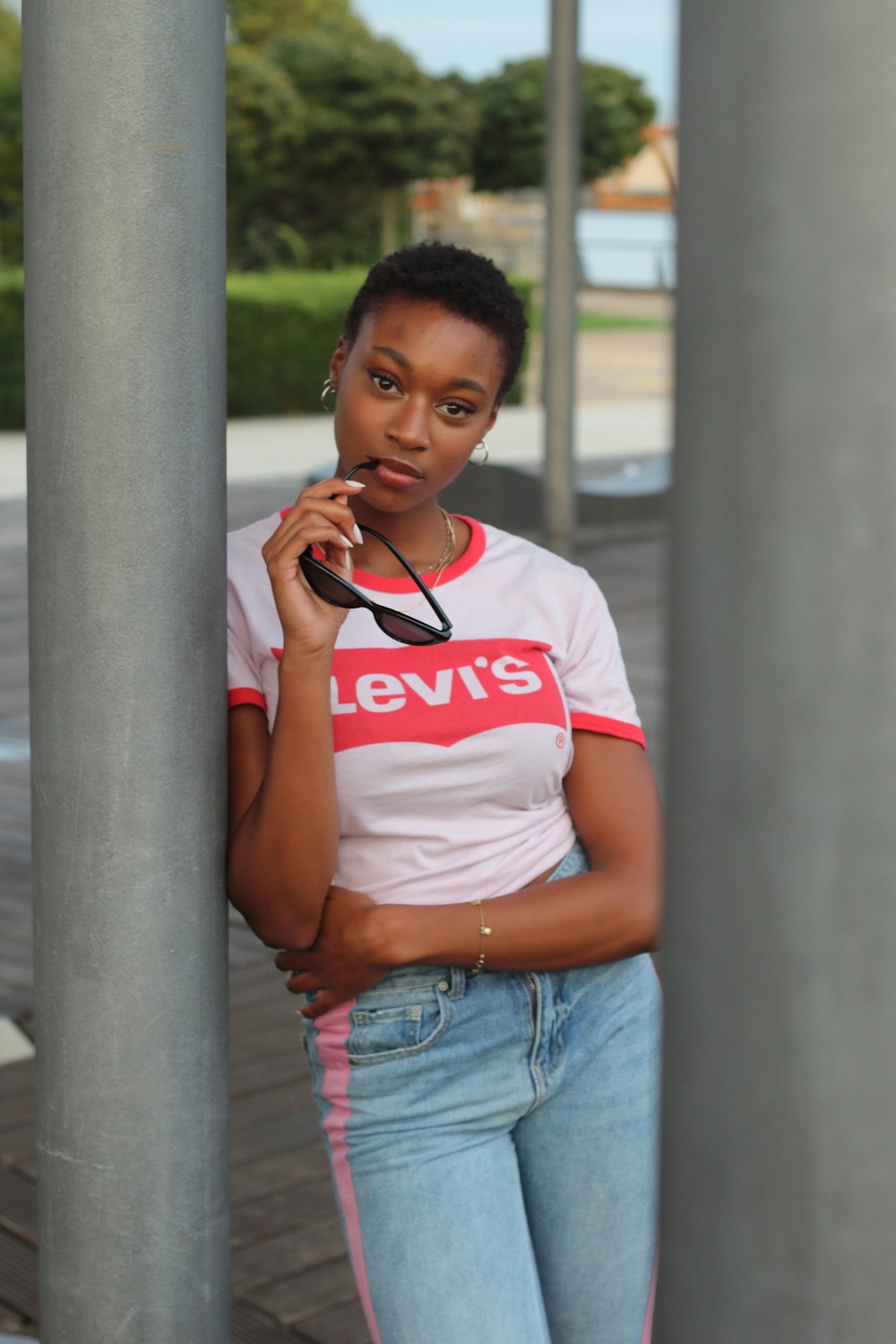 woman in white and red crew neck t-shirt and blue denim jeans leaning on gray