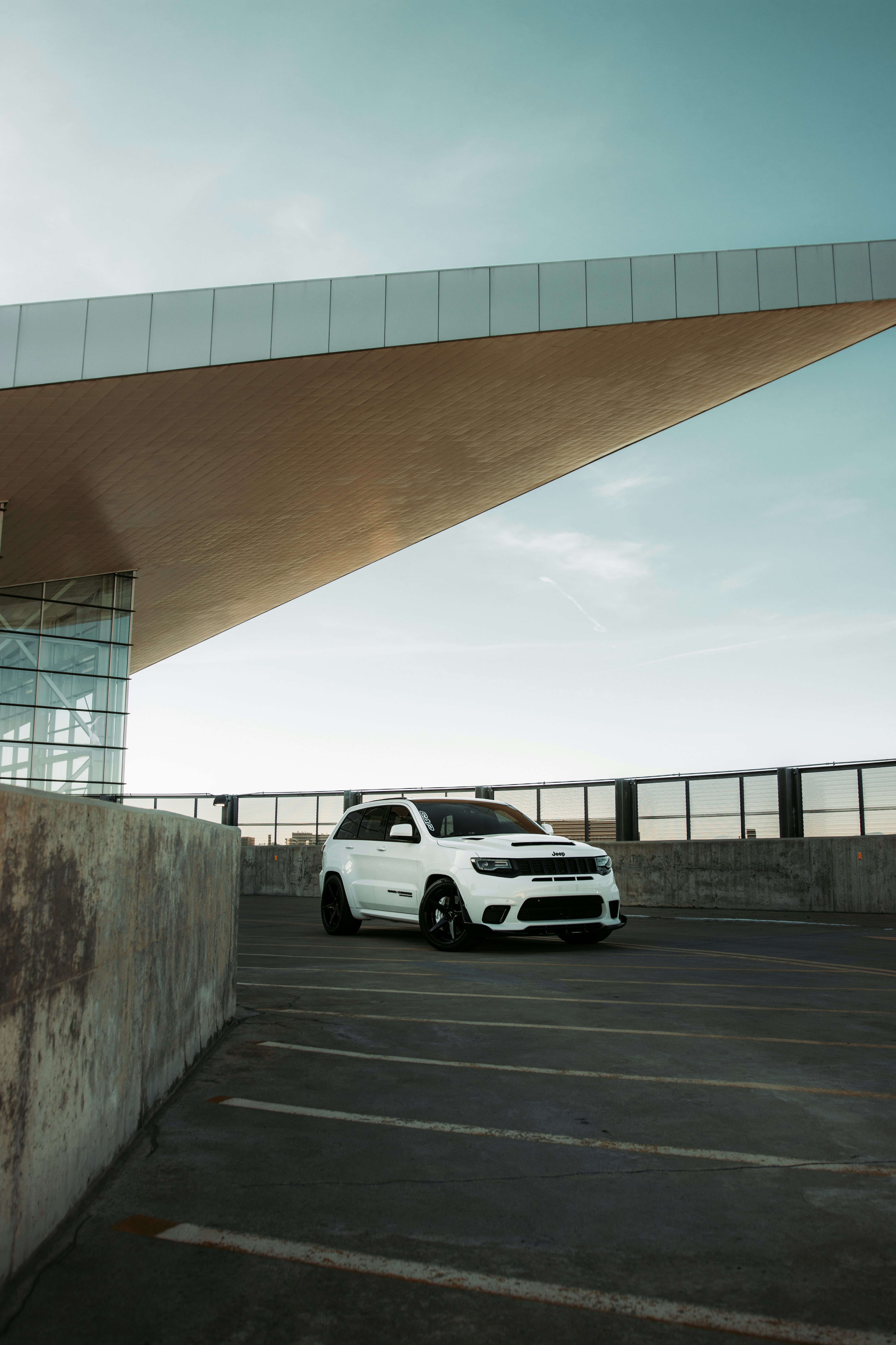 white sedan parked beside gray concrete wall during daytime