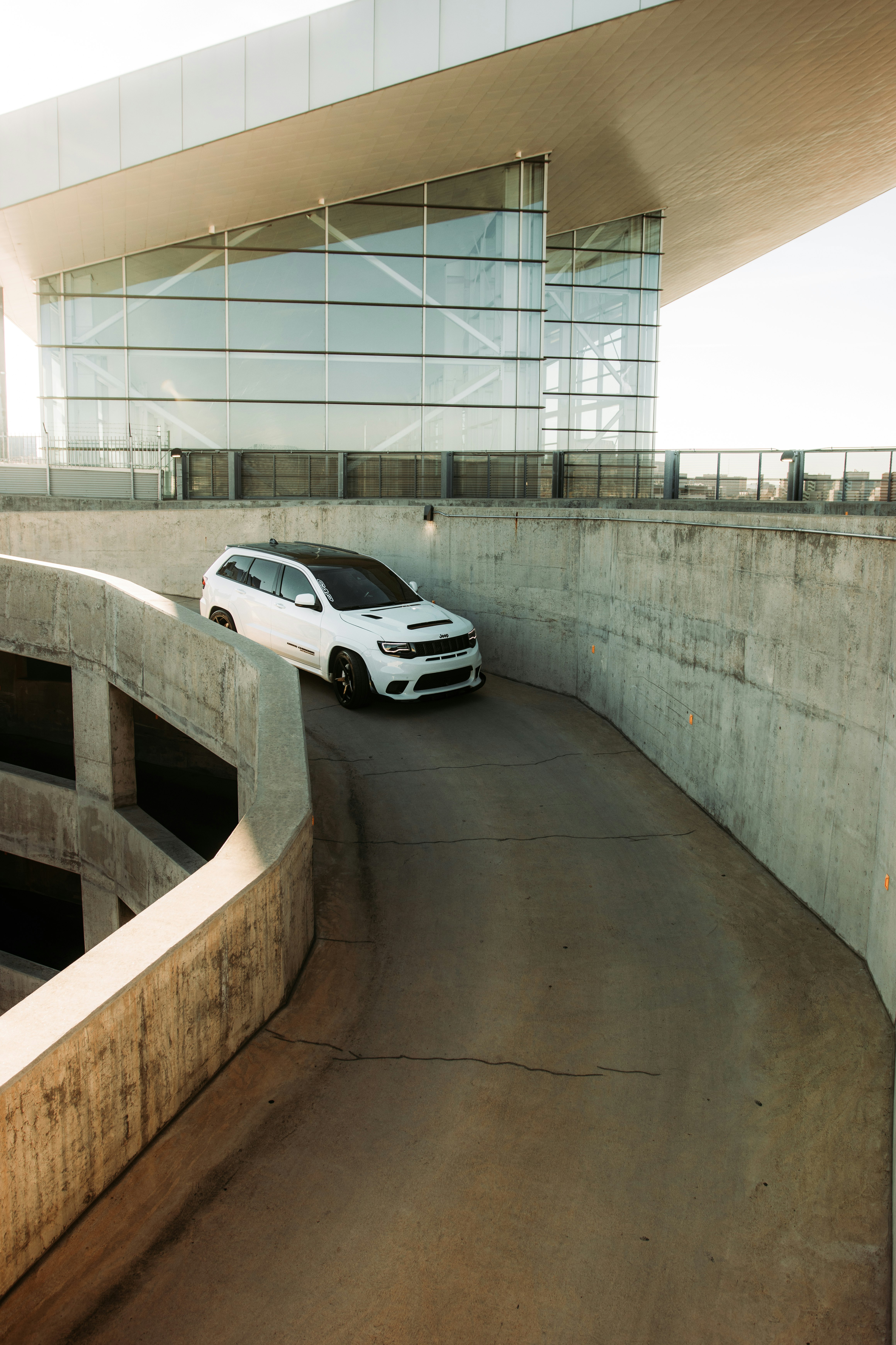 white sedan parked beside gray concrete wall during daytime