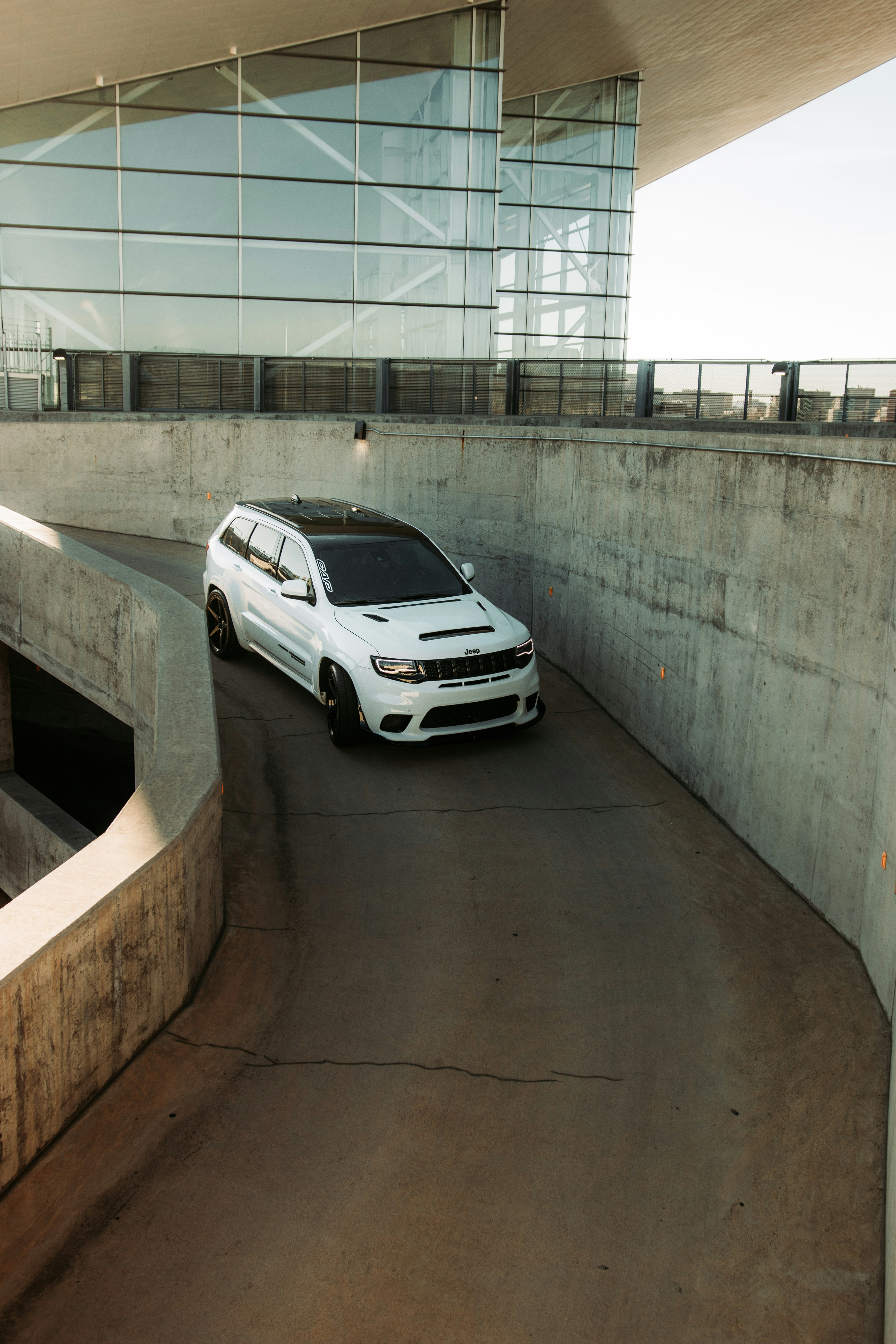white sedan parked beside gray concrete wall
