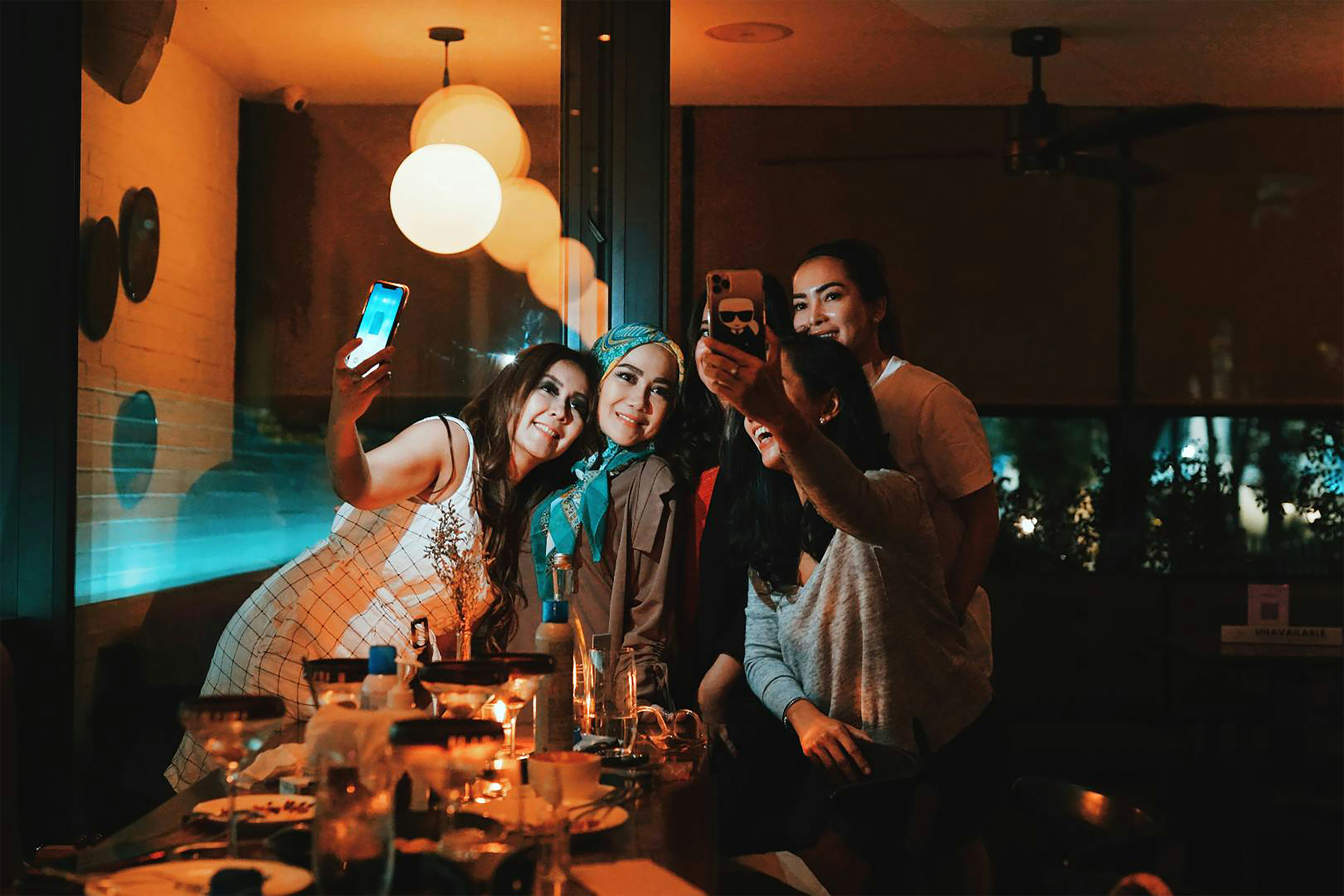 3 women smiling and standing near table, time too selfie
