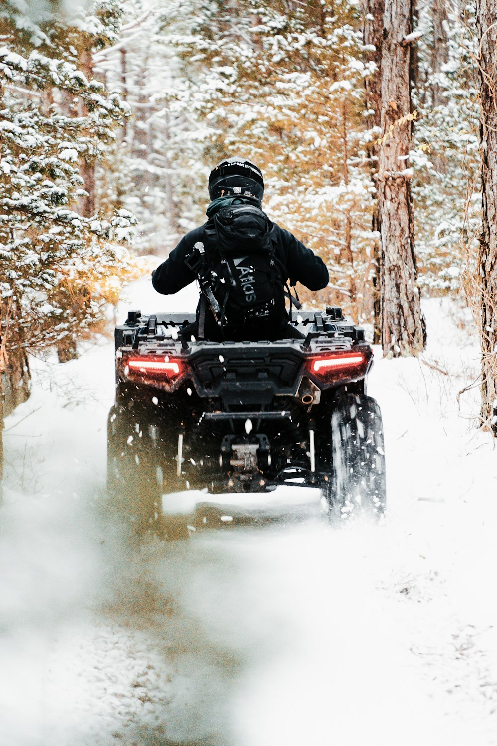 Hombre montando ATV rojo en terreno cubierto de nieve durante el día