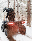 man in black jacket riding on red and black atv on snow covered ground during daytime