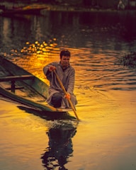 man in yellow and black jacket riding on boat during sunset