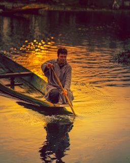 man in yellow and black jacket riding on boat during sunset
