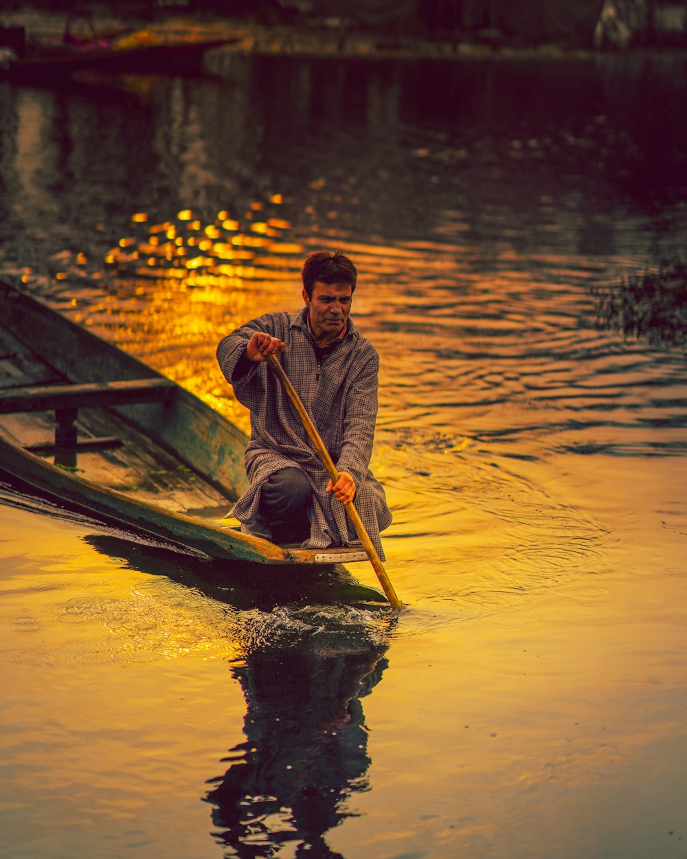 Hombre en chaqueta amarilla y negra montando en barco durante la puesta del sol