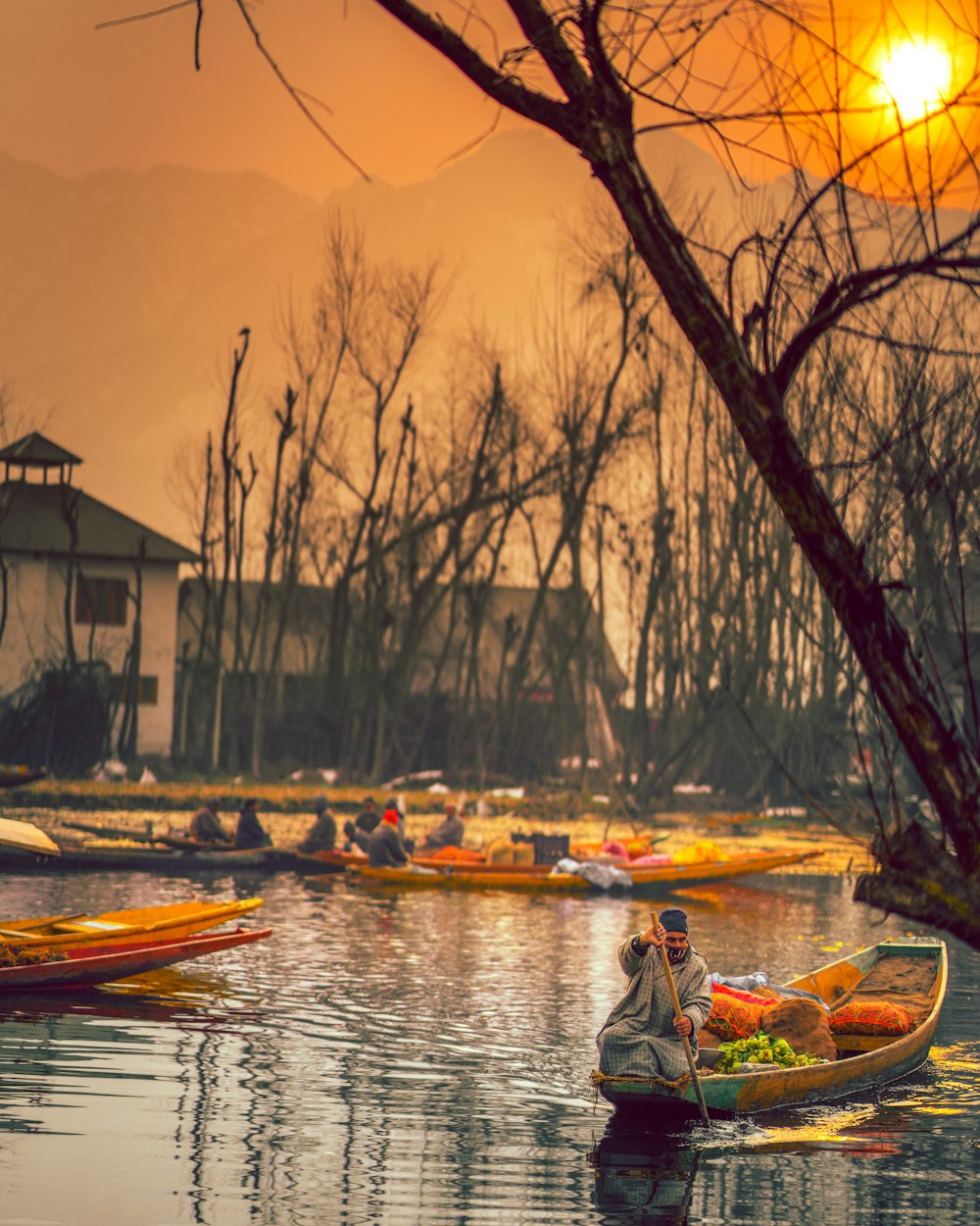 man in blue jacket sitting on boat during sunset