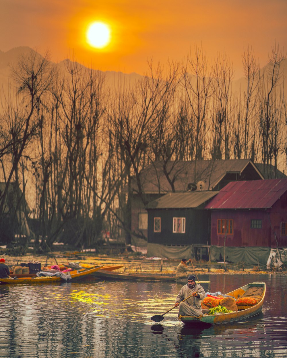 red and black wooden house beside body of water during sunset