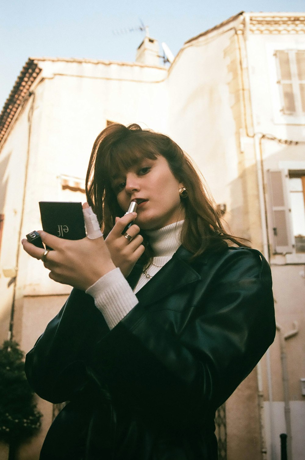 woman in black blazer holding black smartphone