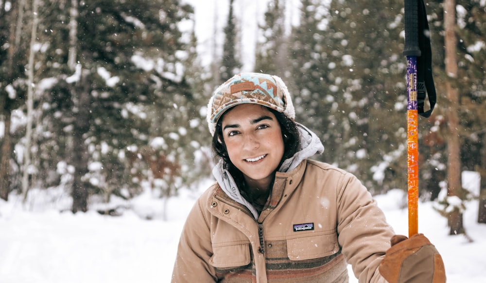 woman in brown jacket standing on snow covered ground during daytime