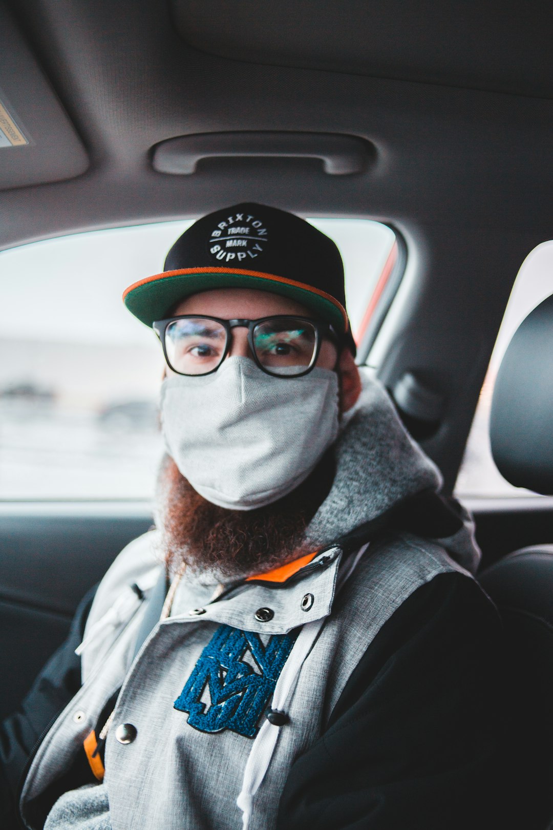 man in black jacket wearing white mask and black and red fitted cap