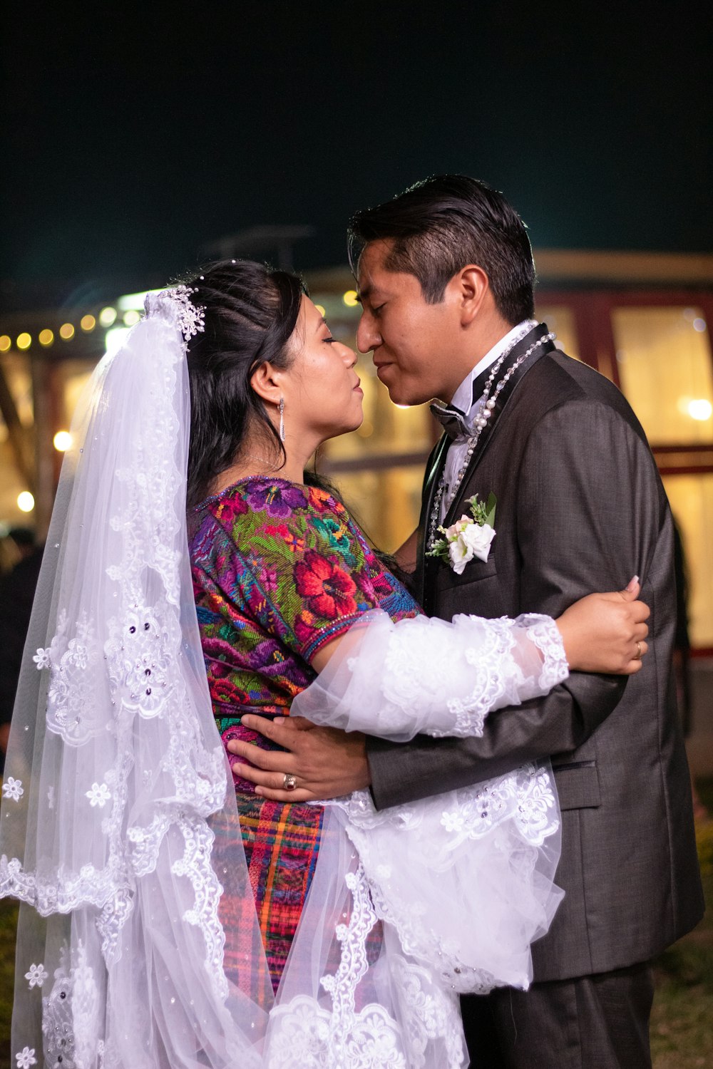 man in black suit kissing woman in white wedding dress