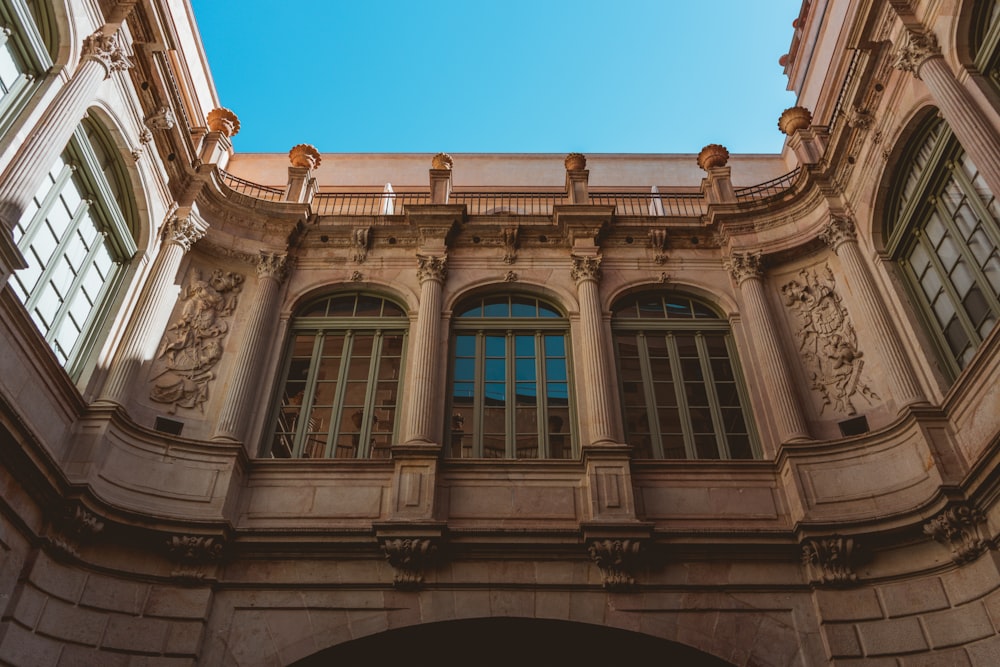 low angle photography of brown concrete building under blue sky during daytime