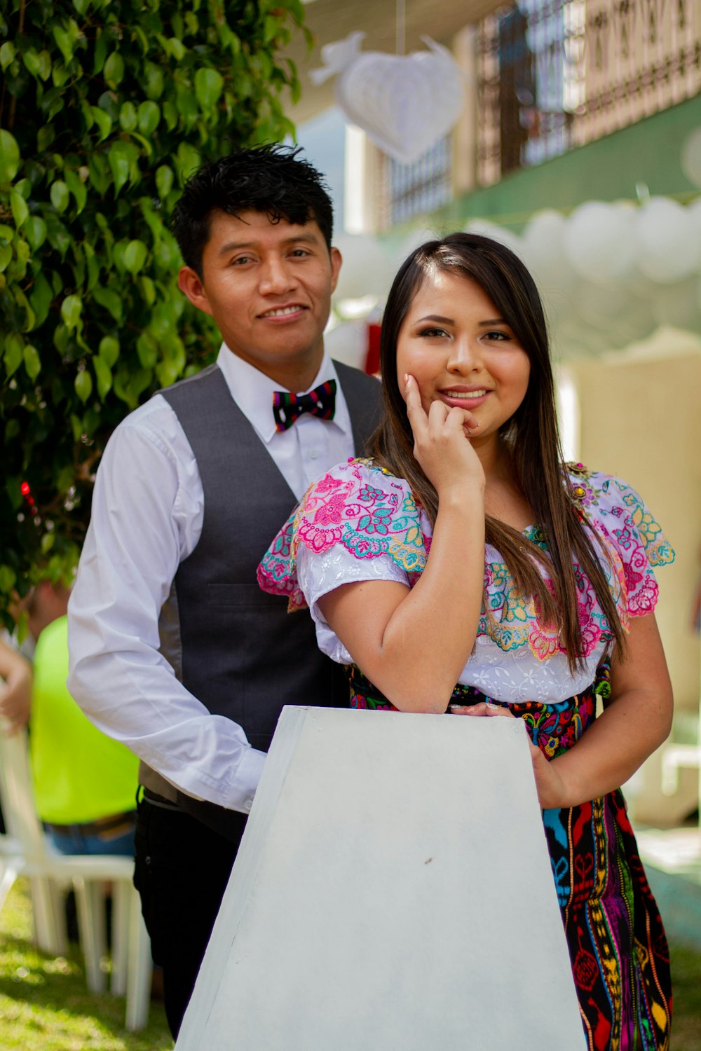 homem na camisa do vestido branco ao lado da mulher no vestido floral cor-de-rosa