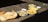 A variety of dishes is spread out on a concrete surface in bright sunlight. The meal includes large crisp papadums, slices of a loaf cake, possibly layered with filling, and what appears to be omelet or scrambled eggs served on oval plates. Small bowls of dipping sauce accompany the dishes.