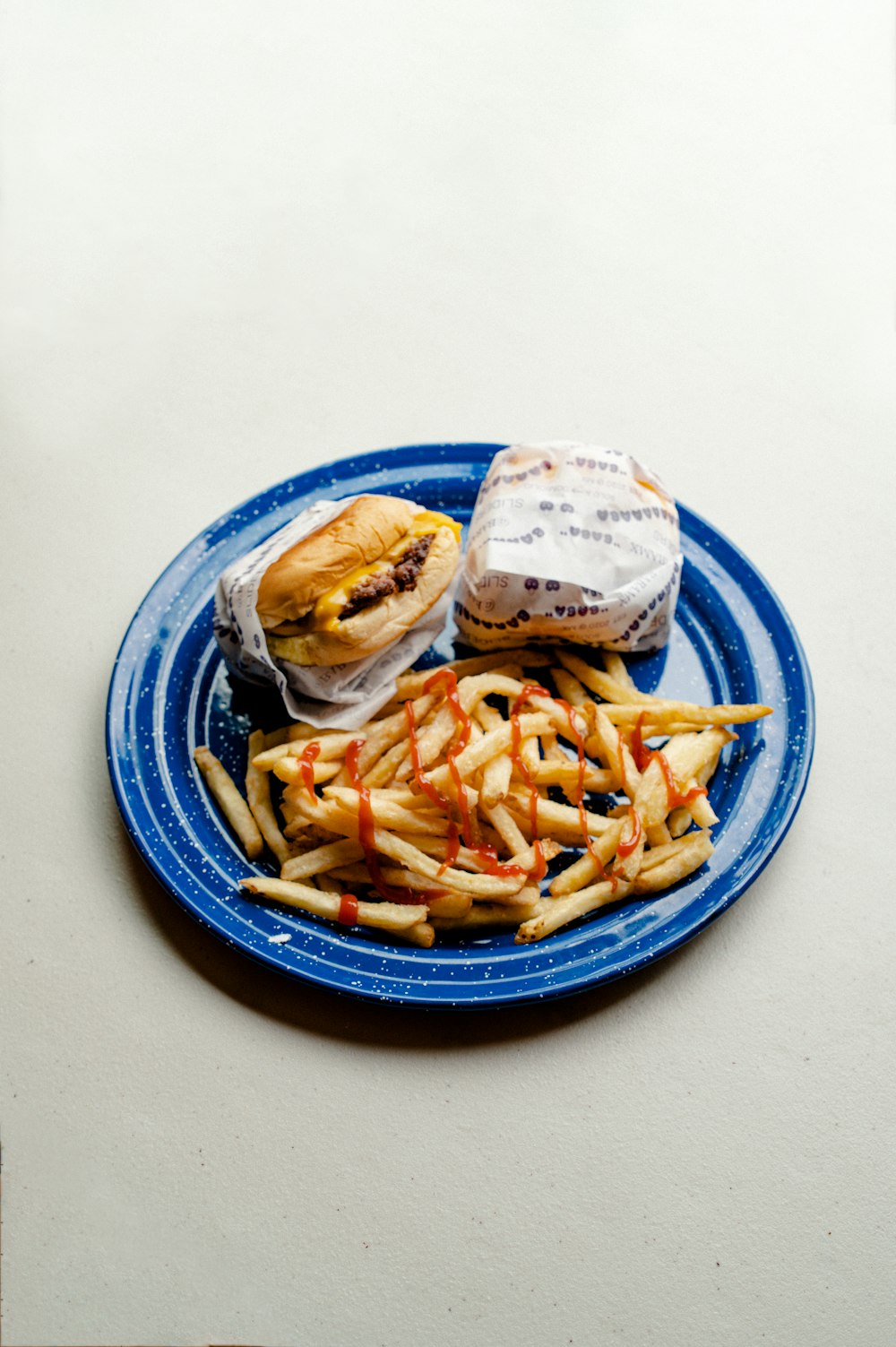 파란색과 흰색 세라믹 접시에 햄버거와 감자 튀김