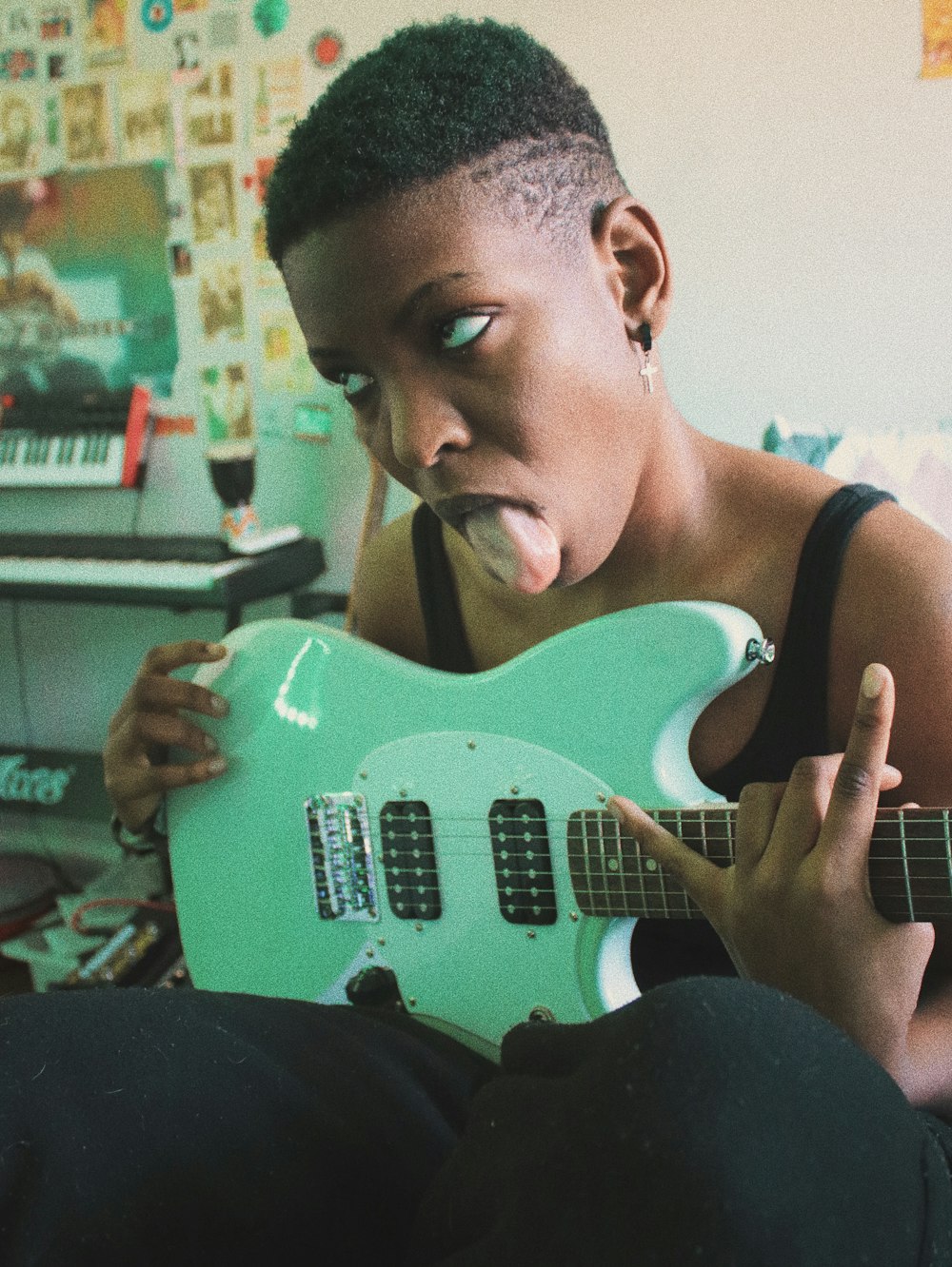 man in black tank top playing electric guitar