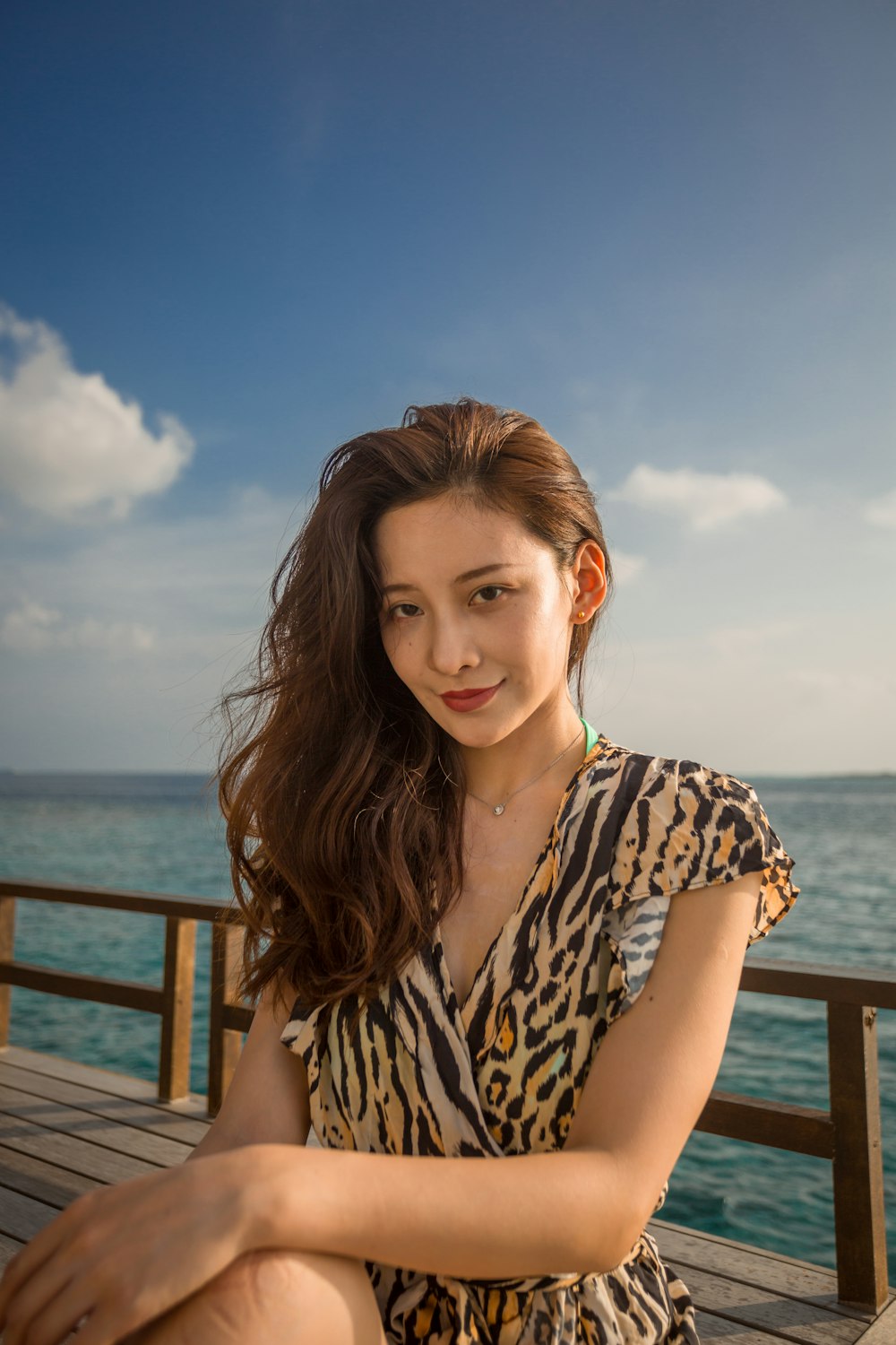 woman in black and white leopard print sleeveless shirt standing on brown wooden dock during daytime