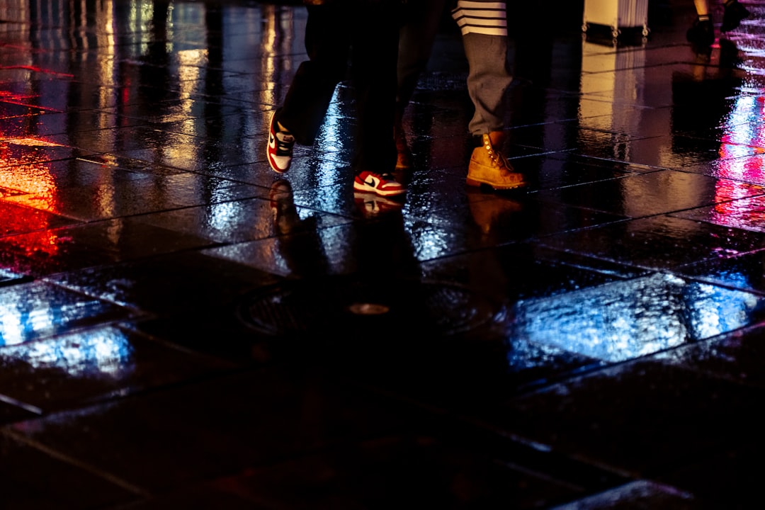 people walking on wet pavement during night time