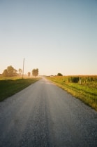 gray asphalt road between green grass field during daytime
