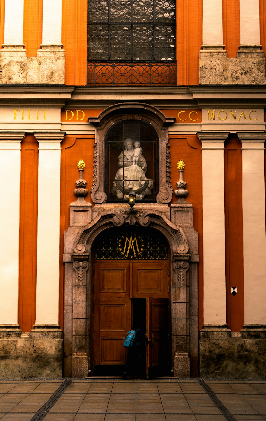 man in blue jacket standing in front of brown concrete building