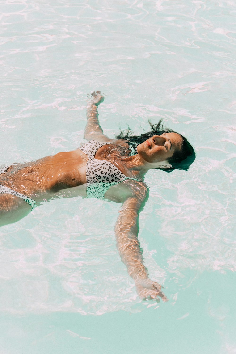 woman in green and white polka dot bikini lying on water