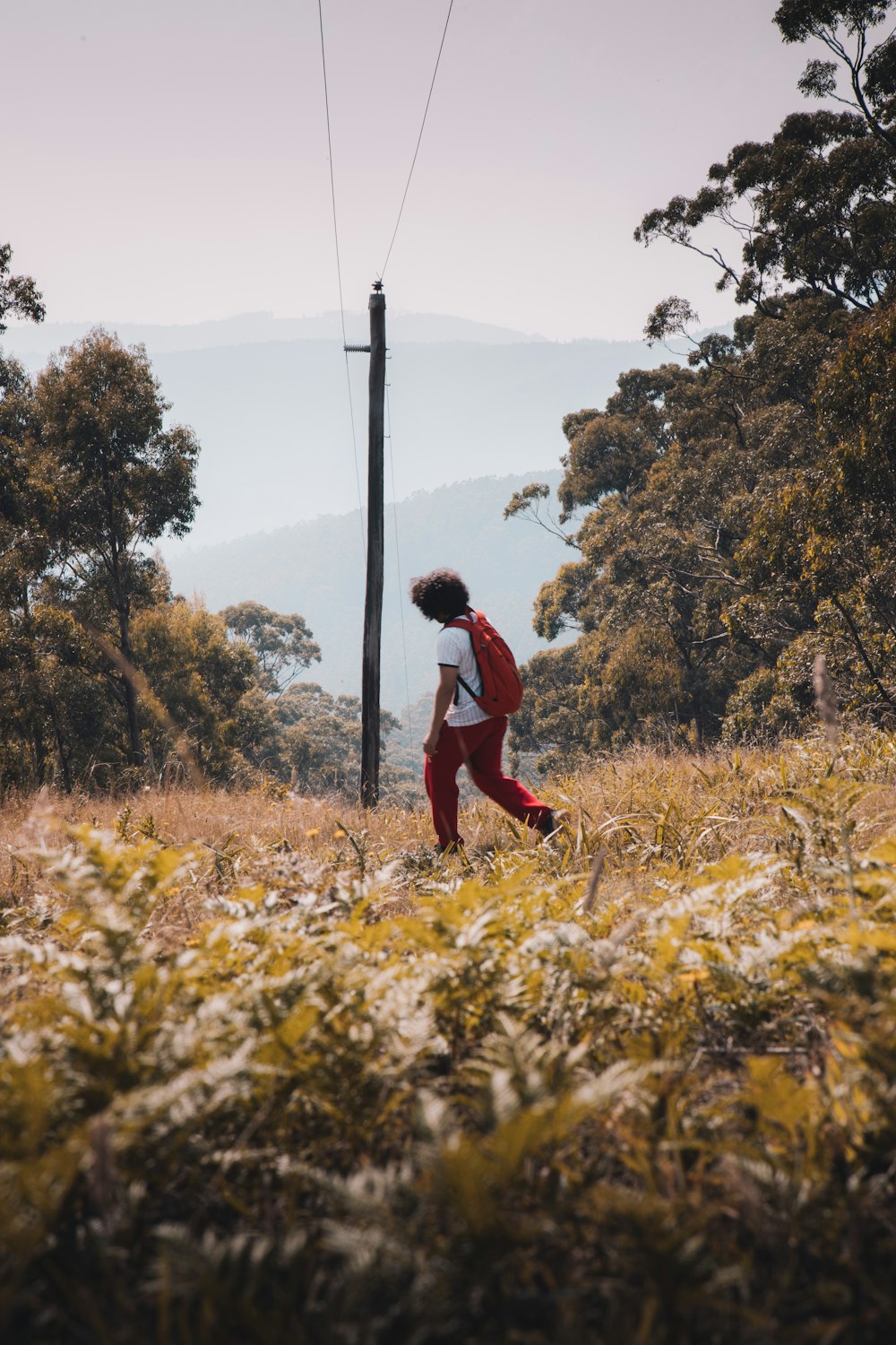 man in red jacket and black pants standing on brown grass field during daytime