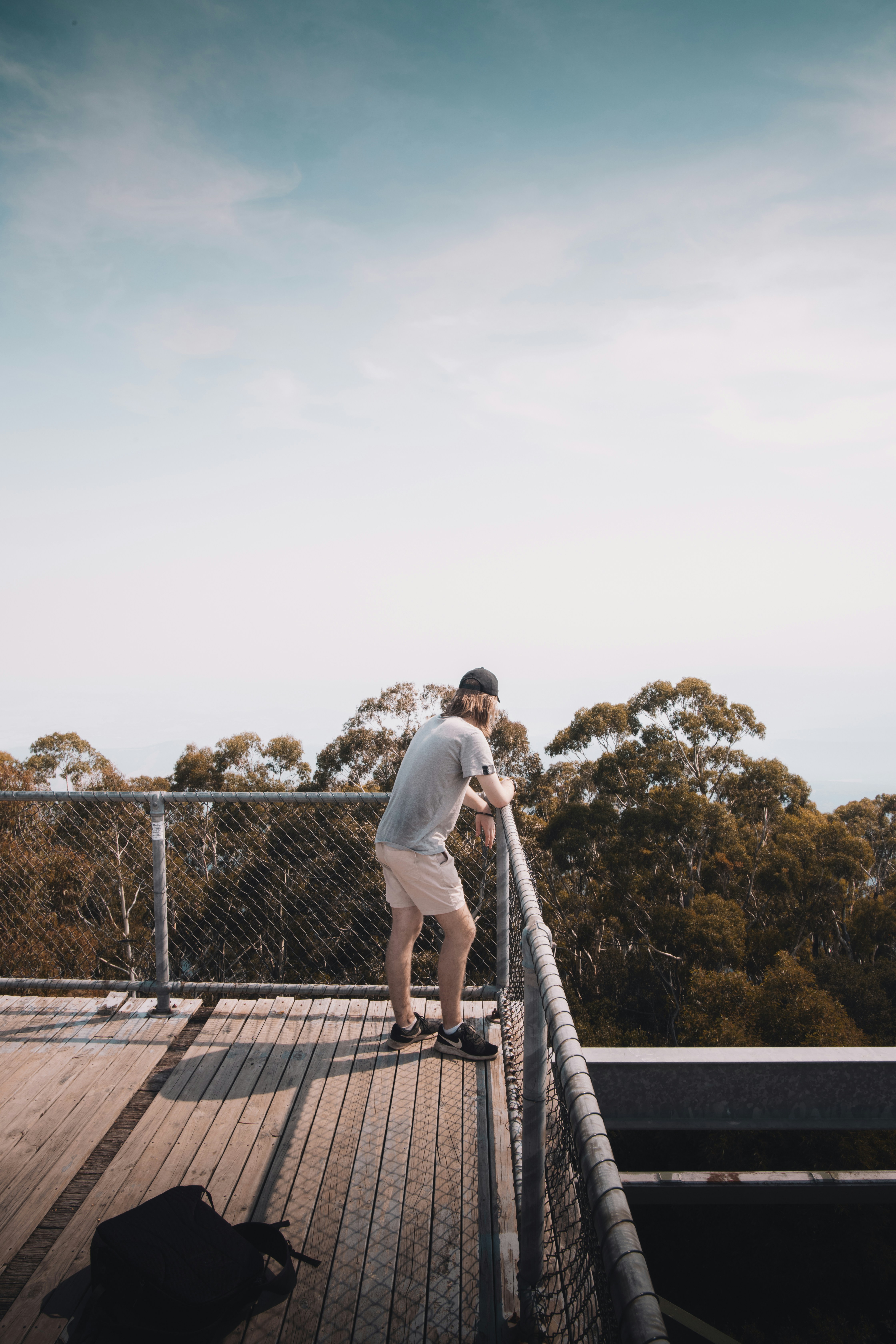 man in white shirt and black pants standing on brown wooden dock during daytime