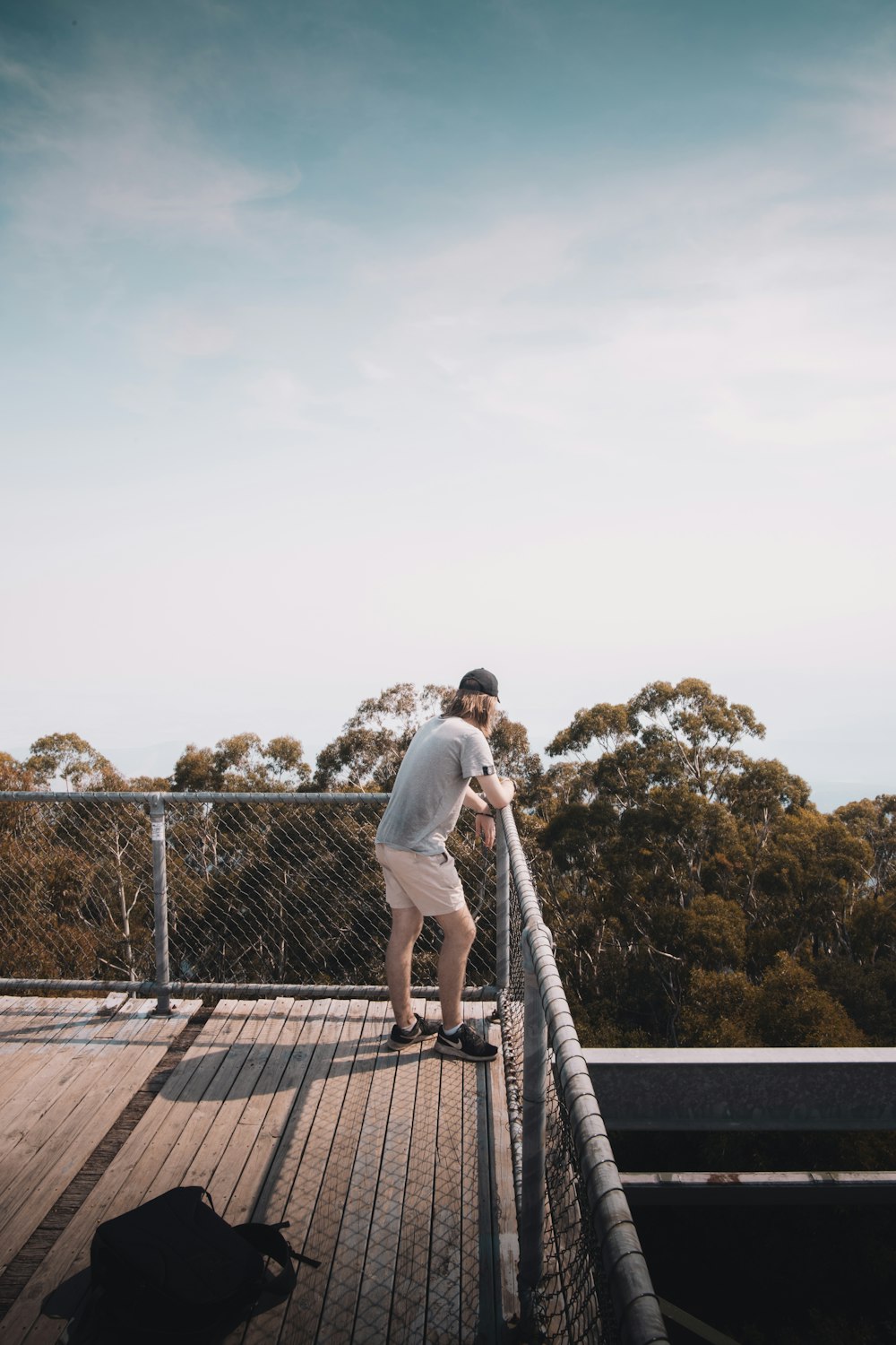 man in white shirt and black pants standing on brown wooden dock during daytime