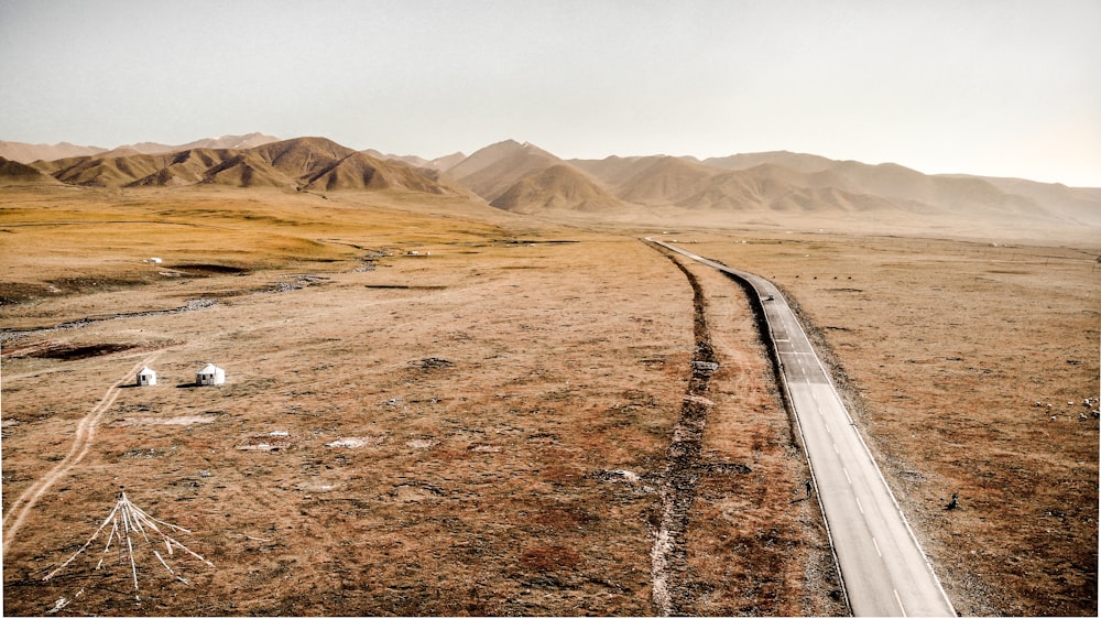 gray concrete road in the middle of brown field