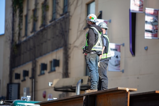 man in green jacket wearing white helmet standing near brown wooden table during daytime