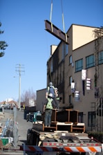 Construction workers installing beams on a modern urban building site.