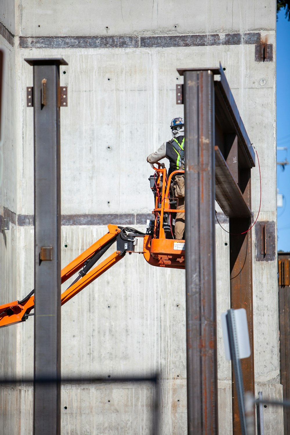 man in orange jacket and black pants riding on orange and black power tool