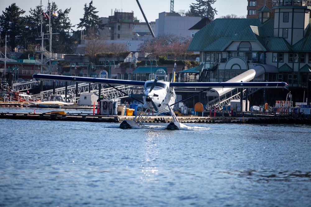 white and blue motor boat on water near green and white building during daytime