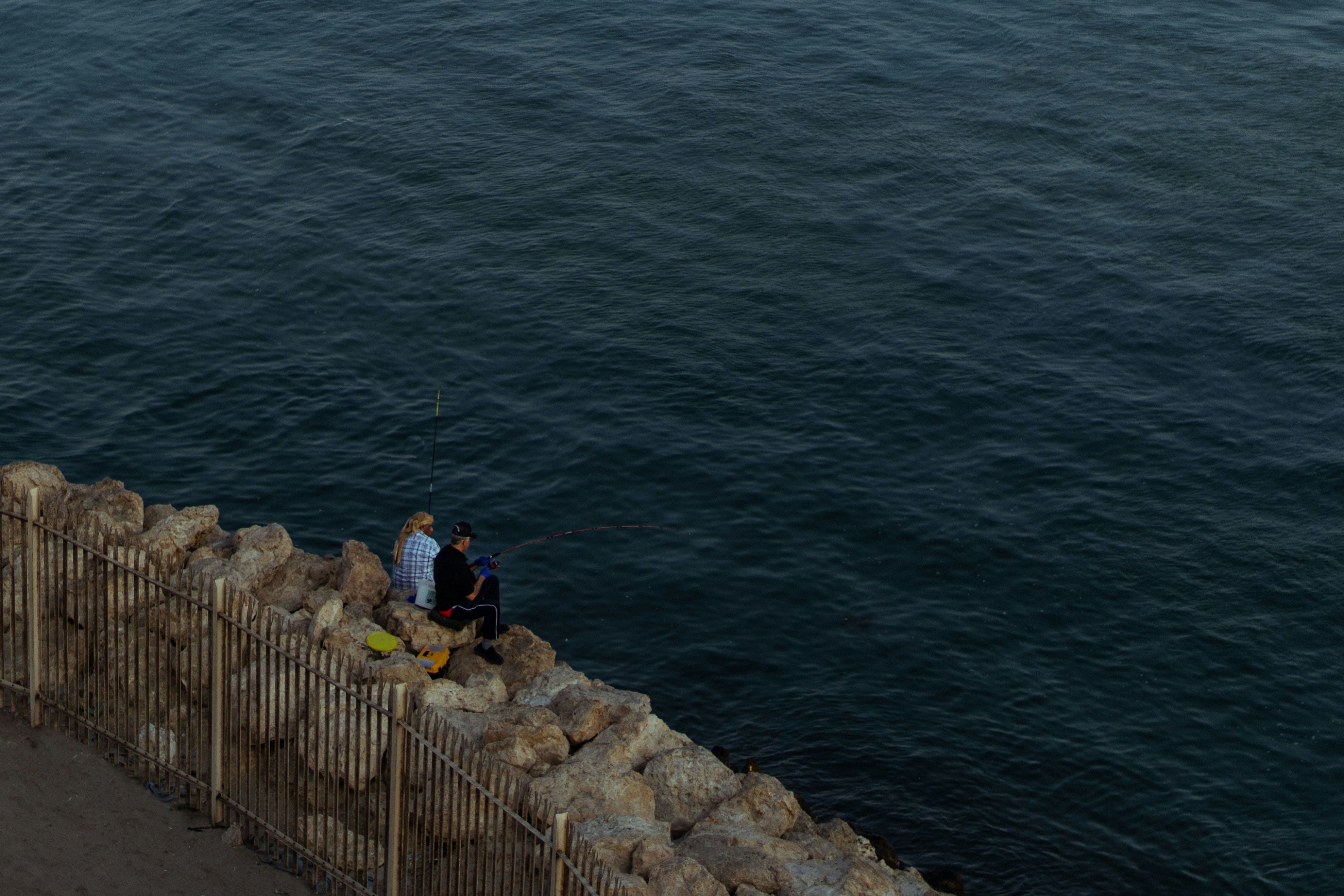 people standing on rock formation near body of water during daytime