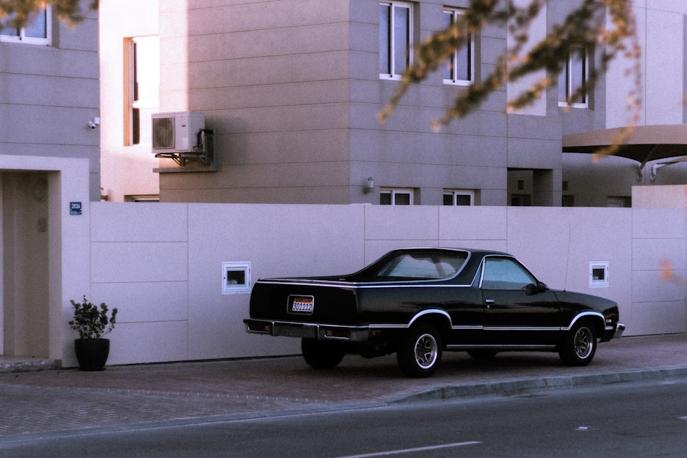 black chevrolet camaro parked in front of white building